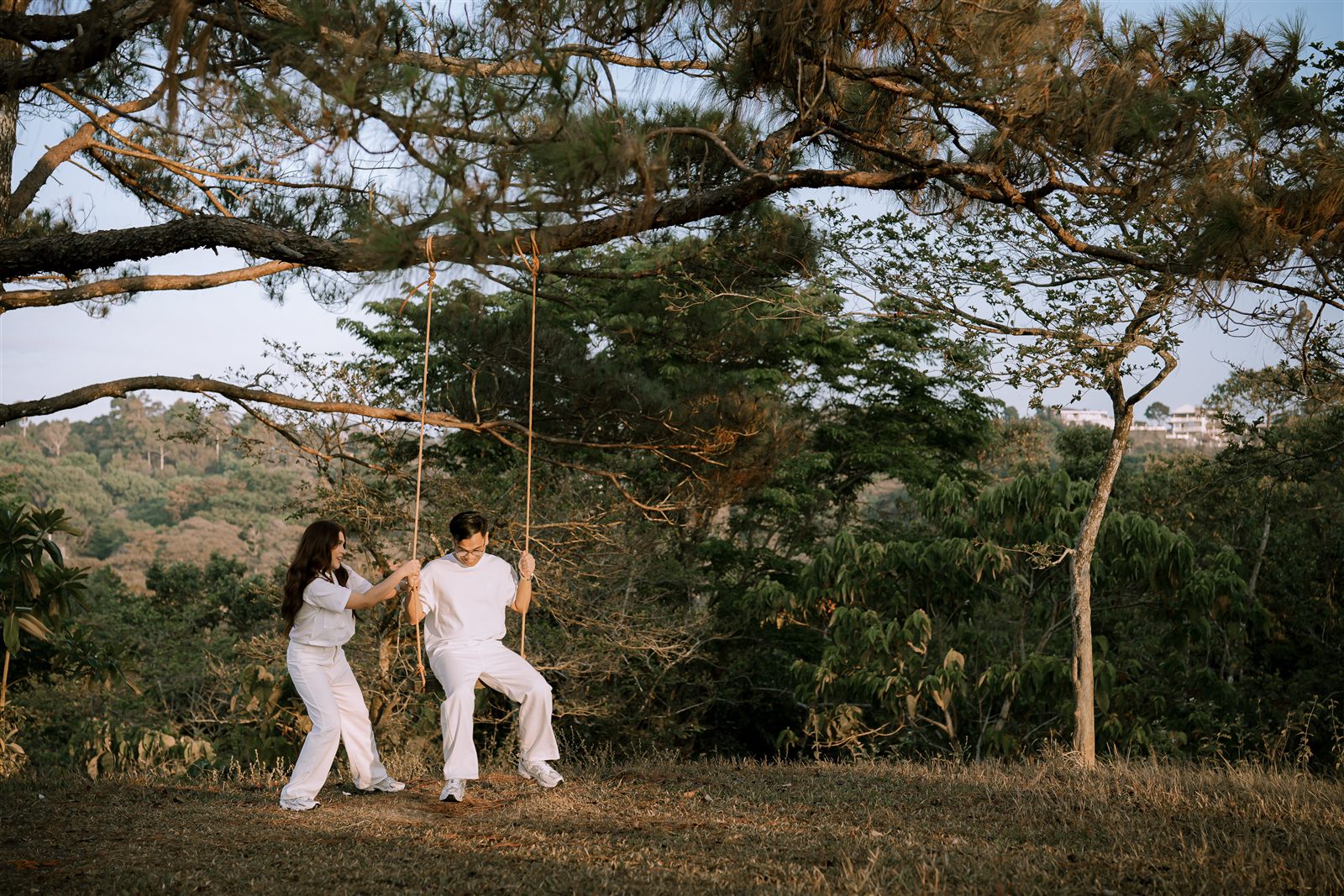 Caren and Zayrol on a swing under golden light